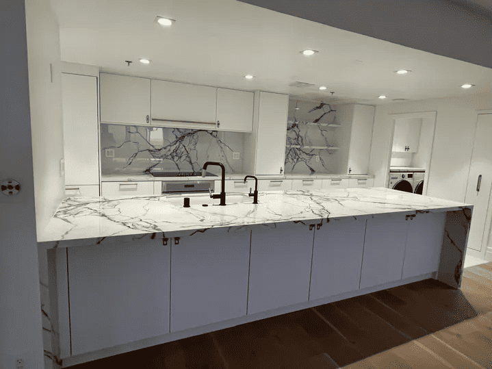 angled view of white kitchen with marble countertops